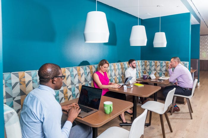 Remote workers working in Carr Workplaces lounge area with vibrant walls.